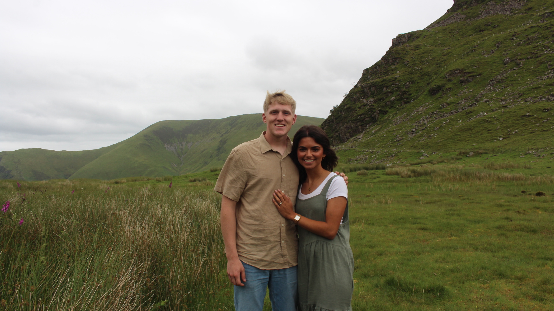AJ and Beth Horton standing together in the green hills of the United Kingdom